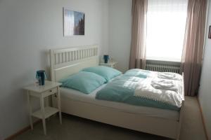 ReppenstedtにあるPrivatzimmer Sutantoの青い枕と窓のあるベッドのある寝室 +4枚の写真