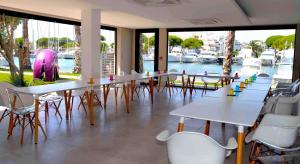 a group of tables and chairs in a room with a marina at Le Spinaker in Le Grau-du-Roi