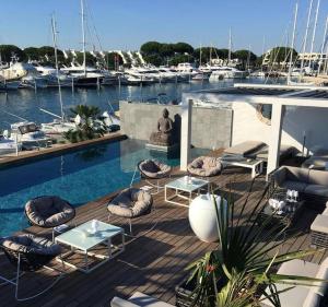 a deck with chairs and tables and boats in a marina at Le Spinaker in Le Grau-du-Roi