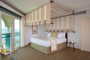 a bedroom with a bed and a large window at Herods Boutique Eilat a Premium collection by Fattal Hotels in Eilat +39 photos