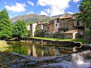 a village with a river and buildings and a waterfall at Apartamentos Rurales El Zarzo in Hervás