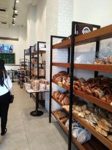 a woman walking through a bakery with shelves of pastries at Namaste in Tel Aviv