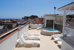 a patio with lounge chairs and a pool on a roof at Hotel Hermes in Tossa de Mar