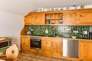 a kitchen with wooden cabinets and green tile at Haus Bürgle in Bad Hindelang