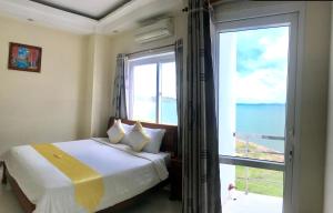 a bedroom with a bed and a large window at Hoang Yen Canary Hotel in Quy Nhon