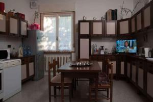 cocina con mesa con sillas y TV en L'incrocio - Appartamento turistico en Imola