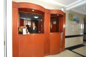 a woman is standing behind an orange door at Royal Plaza Hotel Apartments in Dubai