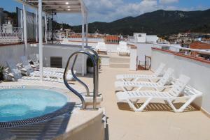 a balcony with white chairs and a swimming pool at Hotel Hermes in Tossa de Mar