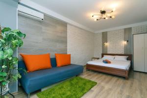 een slaapkamer met een bed en een bank met oranje kussens bij Apartment near Dream Town in Kiev
