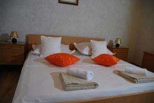 a white bed with orange pillows and towels on it at Apartman Ružica in Makarska