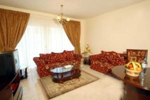 a living room with red couches and a television at Royal Plaza Hotel Apartments in Dubai