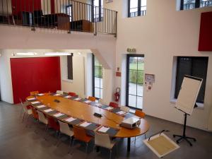 una gran sala de conferencias con una mesa grande y sillas en AUBERGE DU CHÂTEAU BLEU en Tremblay En France