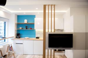 a kitchen with white cabinets and a flat screen tv at Leiland #colony_White_Tower_Suite in Thessaloniki