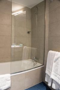 y baño con bañera, ducha y toallas. en Hotel Alda Jolio Jaca, en Jaca
