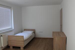 a small bedroom with a bed and a wooden table at Petite Apartment in Maribor