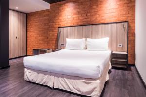 Cama grande en habitación con pared de ladrillo en ONOMO Hotel Durban en Durban