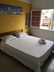 a large white bed in a bedroom with a window at Pousadinha in Ubatuba
