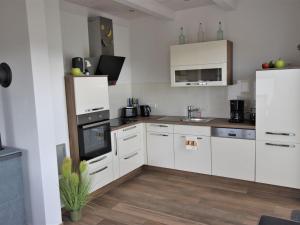 cocina con armarios blancos y suelo de madera en Cozy Holiday Home in Gross Schwansee with Sauna, en Gross Schwansee