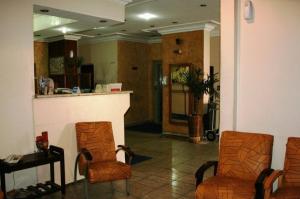 a lobby with two chairs and a counter in a room at Hotel Capriccio São Caetano in São Caetano do Sul