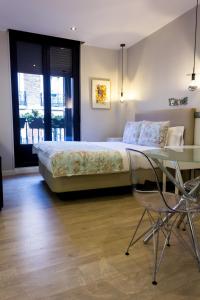 a bedroom with a bed and a table and a chair at Arenal Suites Preciados in Madrid