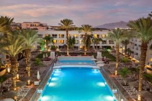 an aerial view of a resort pool with palm trees at Leonardo Royal Resort Eilat in Eilat