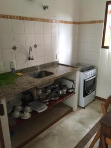 uma cozinha com um lavatório e um balcão com panelas e frigideiras em Vila do Sossego em Ubatuba