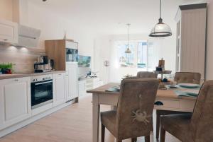 a kitchen with a table and chairs and a kitchen with white cabinets at Baabe Ferienwohnung Lieblingsplatz in Baabe