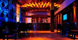 a room with a bar in a building with chairs at Mastiff Grand Manali Resort in Manāli