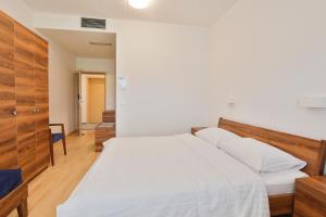 um quarto com uma cama branca e uma cabeceira em madeira em Prenočišča Kogoj em Miren