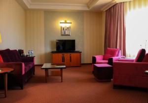 a living room with pink furniture and a flat screen tv at Grand Hotel Europe in Baku