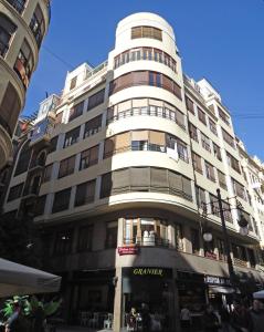 un edificio alto y blanco con gente parada frente a él en Entre la Estación y el Ayuntamiento en Valencia