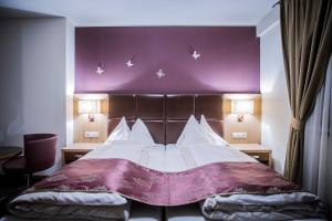 Un dormitorio con una cama grande con una pared morada. en Hotel Flair, en Salzburgo