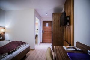 a bedroom with a bed and a desk with a television at Hotel Flair in Salzburg