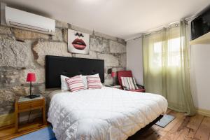 um quarto com uma cama grande e uma parede de pedra em Metro Casa Música Apartments and Rooms no Porto