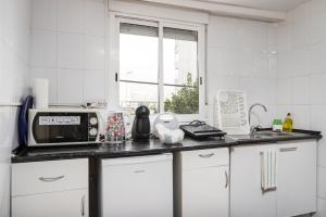 a white kitchen with a microwave and a window at Metro Casa Música Apartments and Rooms in Porto