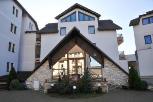 a house with a triangular roof in front of two buildings at Apartman Vlada b14 in Kopaonik