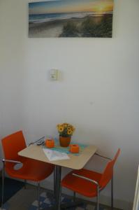 einen Tisch mit orangenen Stühlen und ein Bild an der Wand in der Unterkunft Amsterdam Beach Apartment in Zandvoort