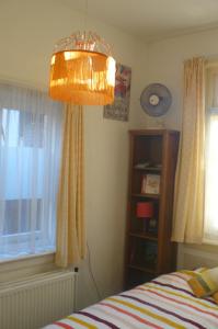 a bedroom with a bed and a chandelier and a window at Amsterdam Beach Apartment in Zandvoort