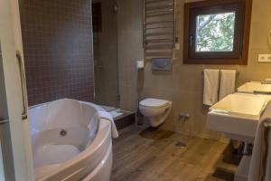 a bathroom with a tub and a toilet and a sink at Los Ojos de la Mora Apartamentos Boutique in Cuenca