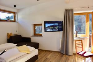 a living room with a couch and a tv on the wall at Pension Norika in Saalbach Hinterglemm