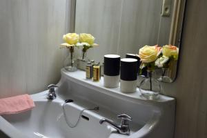 a bathroom with a sink with flowers on a mirror at Auberge Le Relais in Corbion