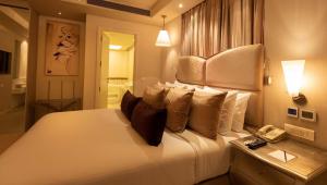 a bedroom with a large white bed with a telephone at Clarens Hotel in Gurgaon