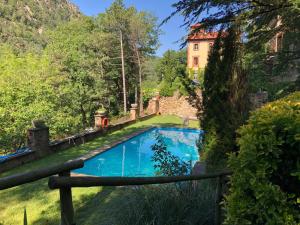 a swimming pool in a garden with a house in the background at Els Apartaments del bosc in Ribes de Freser