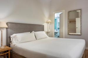 sypialnia z dużym białym łóżkiem i lustrem w obiekcie Suites Sevilla Plaza w Sewilli