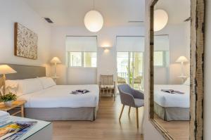 pokój hotelowy z dwoma łóżkami i lustrem w obiekcie Suites Sevilla Plaza w Sewilli