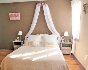 sypialnia z białym łóżkiem z baldachimem w obiekcie La Chapelle du Chateau Lagarrigue w mieście Strenquels