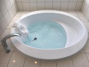 een badkamer met een bad gevuld met blauw water bij シーブリーズ古宇利 in Nakijin