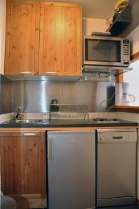 eine Küche mit Holzschränken, einer Mikrowelle und einem Geschirrspüler in der Unterkunft Les Melezets 1 in Valfréjus
