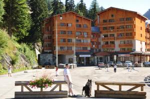 a man walking a dog in front of a building at Les Melezets 1 in Valfréjus