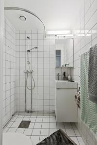 a white tiled bathroom with a shower and a sink at Nordic Host - City Center 2 Bed / 2 Bath - Skippergata - 3 minutes from station in Oslo